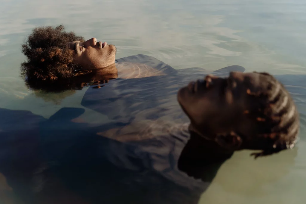 Fotografía artística de dos personas flotando serenamente en agua tranquila, capturada por Cottonbro Studio3, evocando la necesidad de conservación y documentación de obras de arte.
